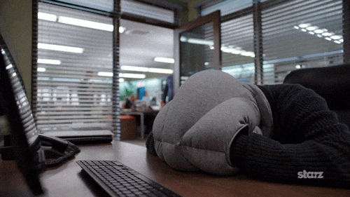 Man in an office sleeping in a foam helmet gets woken up and startled by a colleague